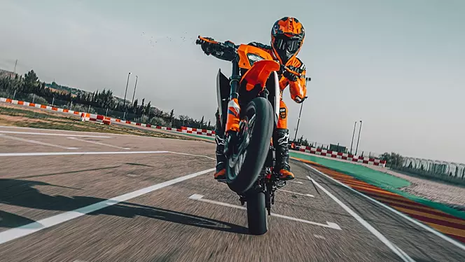 Rider performing a wheelie on the KTM 390 SMC R on a racetrack